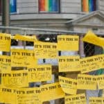 Yellow posters in front of Portland City Hall that say "It's time to:" with notes completed by activists. For example, "Its time to: Stop burning fossil fuels".