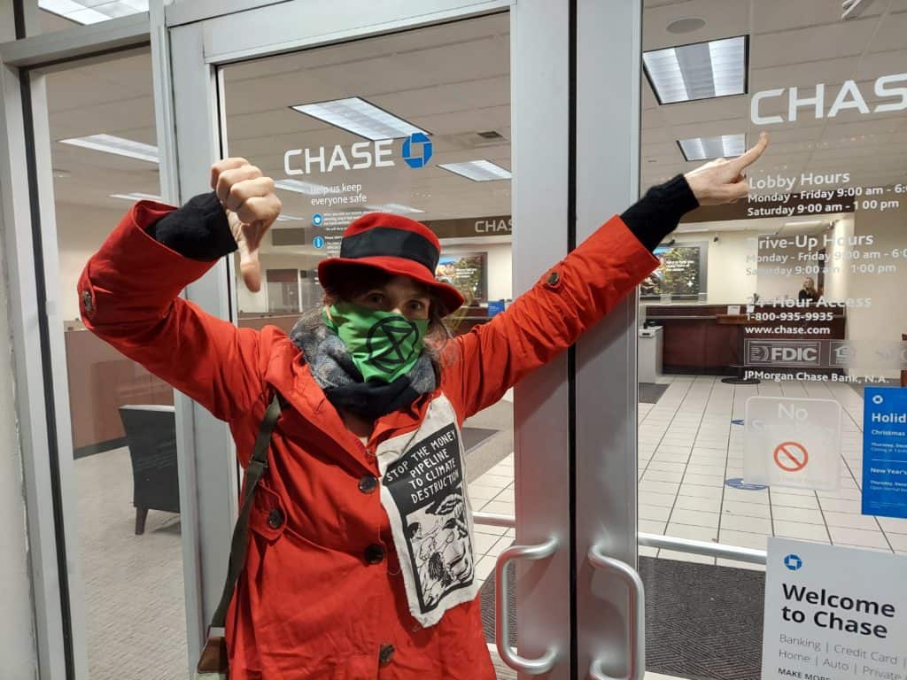 A member of XRPDX giving a thumbs down outside the front entrance of a Chase Bank