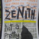 A screenprinted fabric that might be attached to a bag or jacket. It reads "ZENITH" over stylized barbed wire, above a grey brick wall which says "Note a pretty site." Oil drips down fron the N in Zenith to form a black mass down the wall. In the white space above the barbed wire, the words "TAR SANDS OIL" are written over and over in light orange.