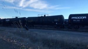 An oil train rolling into Zenith Energy. The sky is blue with wispy clouds.