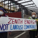 Two women holding banner that says "Zenith Energy Not Land Use Compatible