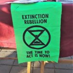 Small green banner with words "Extinction Rebellion The Time To Act Is Now"
