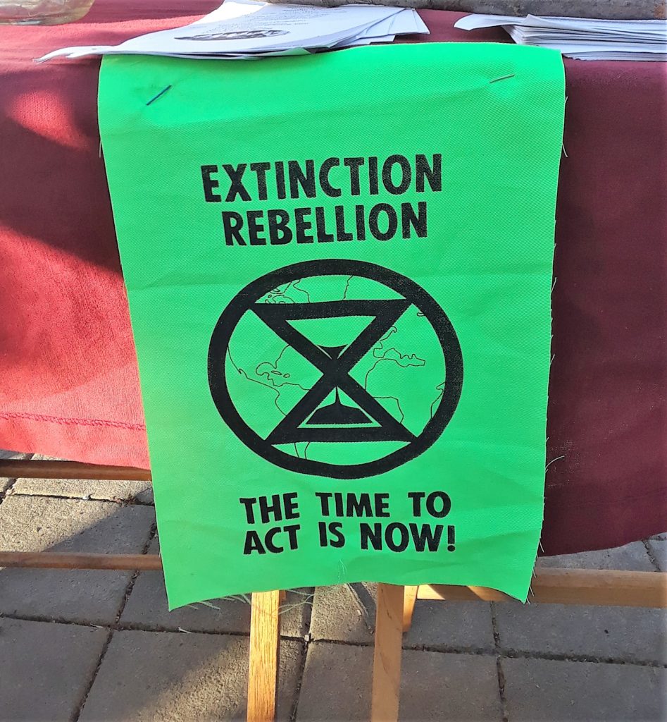 Small green banner with words "Extinction Rebellion The Time To Act Is Now"
