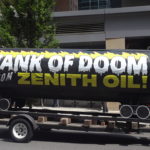 Large black prop simulating an oil train tank car, with "Tank of Doom" written on it.